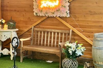 Salle en bois avec des bancs alignés sur un sol en gazon synthétique, décorée de fleurs suspendues.