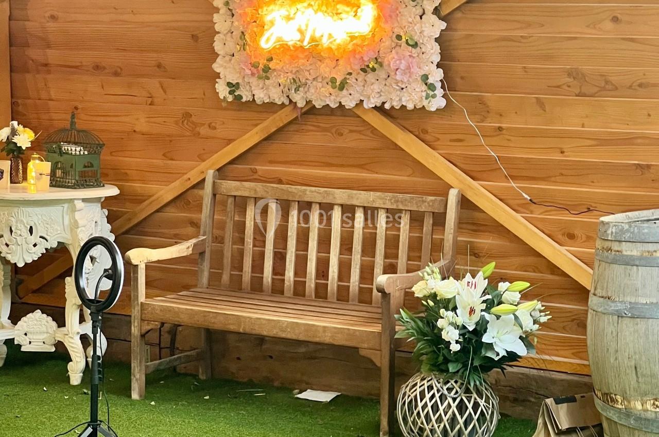 Banc en bois devant un mur en bois décoré de fleurs, d'une enseigne lumineuse et d'éléments de décoration.