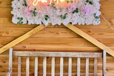 Salle en bois avec des bancs alignés sur un sol en gazon synthétique, décorée de fleurs suspendues.