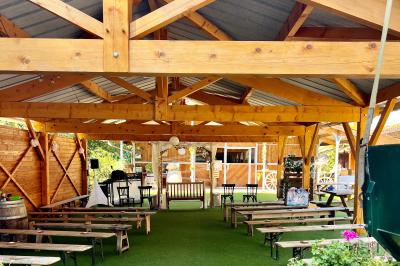 Salle en bois avec des bancs alignés sur un sol en gazon synthétique, décorée de fleurs suspendues.