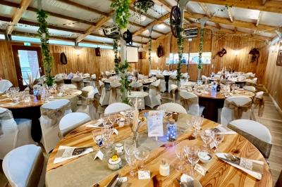 Salle en bois avec des bancs alignés sur un sol en gazon synthétique, décorée de fleurs suspendues.