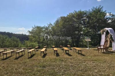 Salle en bois avec des bancs alignés sur un sol en gazon synthétique, décorée de fleurs suspendues.