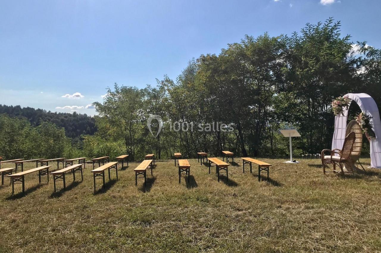 Chaises et bancs disposés en extérieur sur une pelouse, face à une arche décorée pour une cérémonie en plein air.