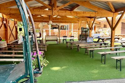 Salle en bois avec des bancs alignés sur un sol en gazon synthétique, décorée de fleurs suspendues.