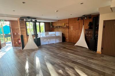 Salle en bois avec des bancs alignés sur un sol en gazon synthétique, décorée de fleurs suspendues.
