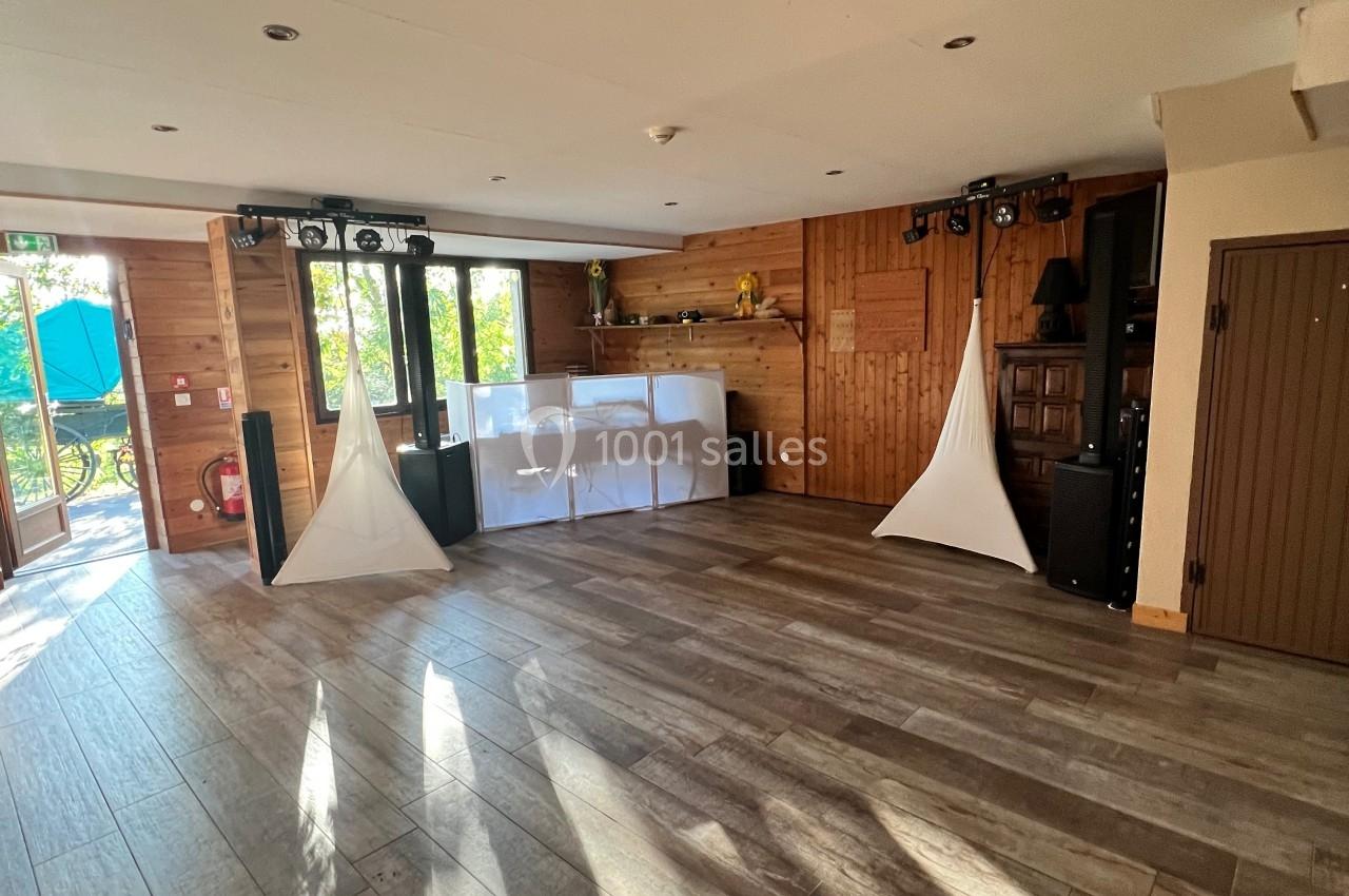 Salle en bois lumineuse avec parquet, équipements audio, décorations blanches et vue sur l'extérieur par des portes vitrées.