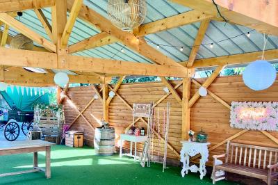 Salle en bois avec des bancs alignés sur un sol en gazon synthétique, décorée de fleurs suspendues.