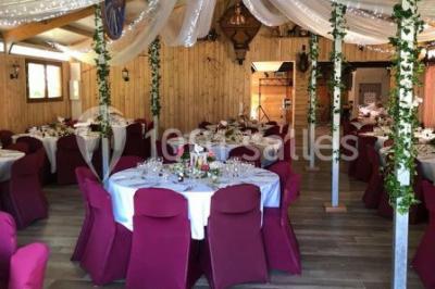 Salle en bois avec des bancs alignés sur un sol en gazon synthétique, décorée de fleurs suspendues.