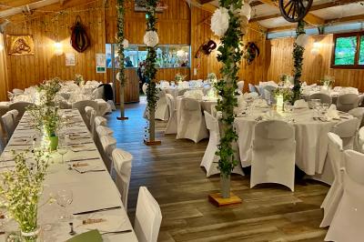 Salle en bois avec des bancs alignés sur un sol en gazon synthétique, décorée de fleurs suspendues.