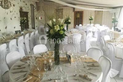 Salle décorée avec des tables hautes blanches, des nappes et des éléments suspendus dans un style épuré et chaleureux.