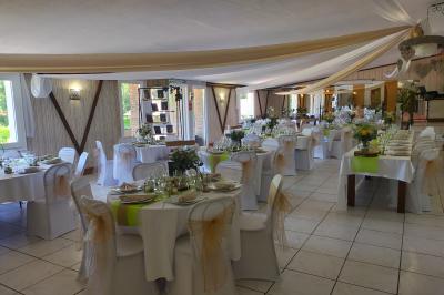 Salle décorée avec des tables hautes blanches, des nappes et des éléments suspendus dans un style épuré et chaleureux.