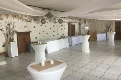 Salle décorée avec des tables hautes blanches, des nappes et des éléments suspendus dans un style épuré et chaleureux.