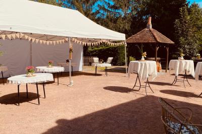 Salle décorée avec des tables hautes blanches, des nappes et des éléments suspendus dans un style épuré et chaleureux.