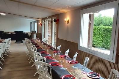 Décoration festive avec arche de ballons rouges, noirs et dorés, rideau scintillant et tapis rouge dans une salle.