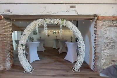 Salle de réception avec une table ronde décorée, des ballons et une grande table dressée en arrière-plan.