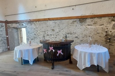Salle de réception avec une table ronde décorée, des ballons et une grande table dressée en arrière-plan.