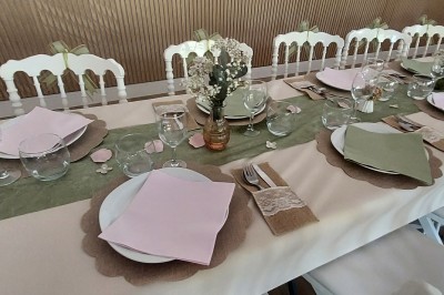 Salle de réception avec une table ronde décorée, des ballons et une grande table dressée en arrière-plan.