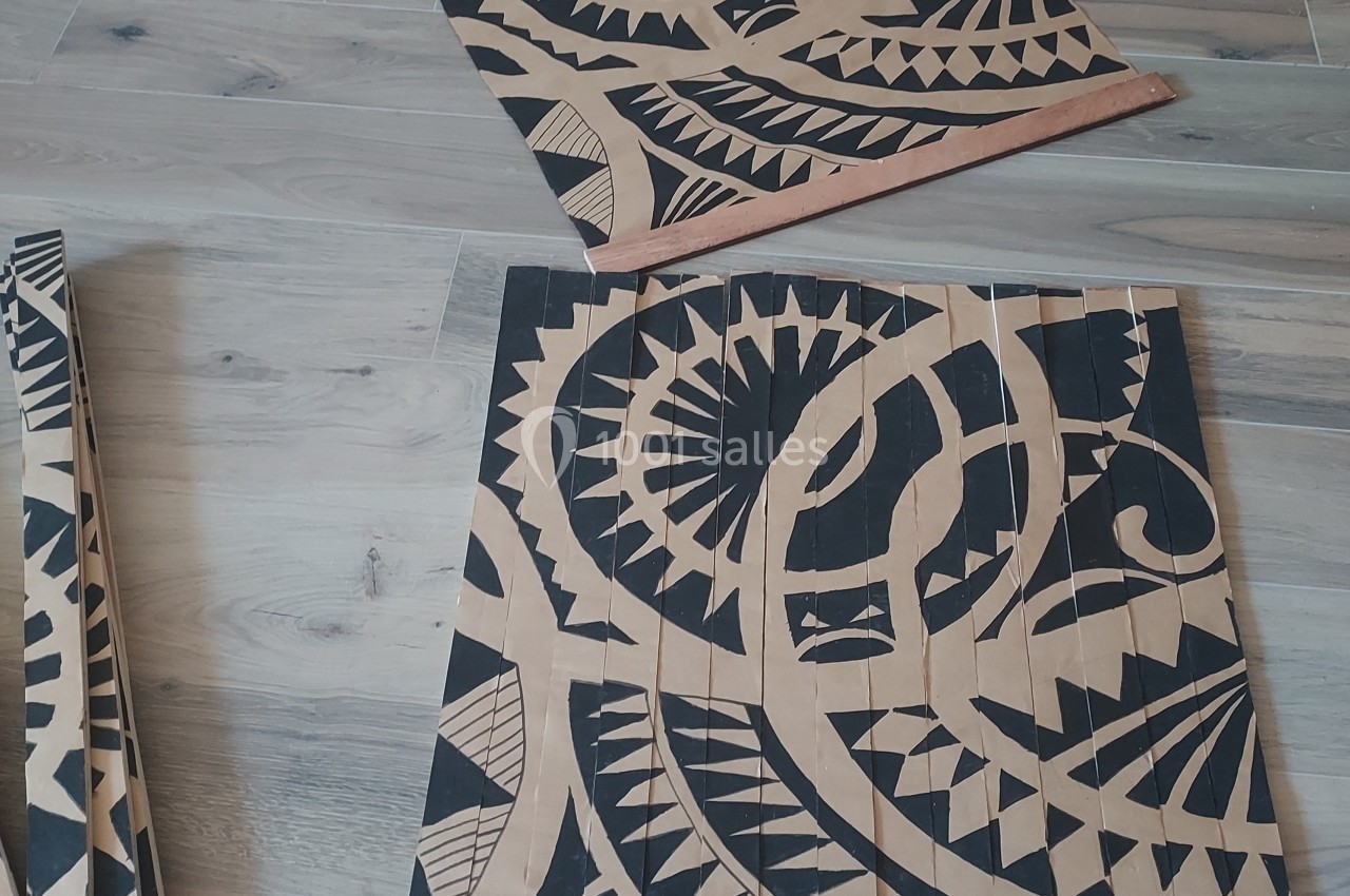 Panneaux en bois décorés de motifs noirs géométriques et tribaux, posés sur un sol en parquet clair.