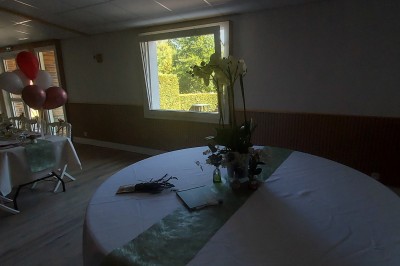 Salle de réception avec une table ronde décorée, des ballons et une grande table dressée en arrière-plan.
