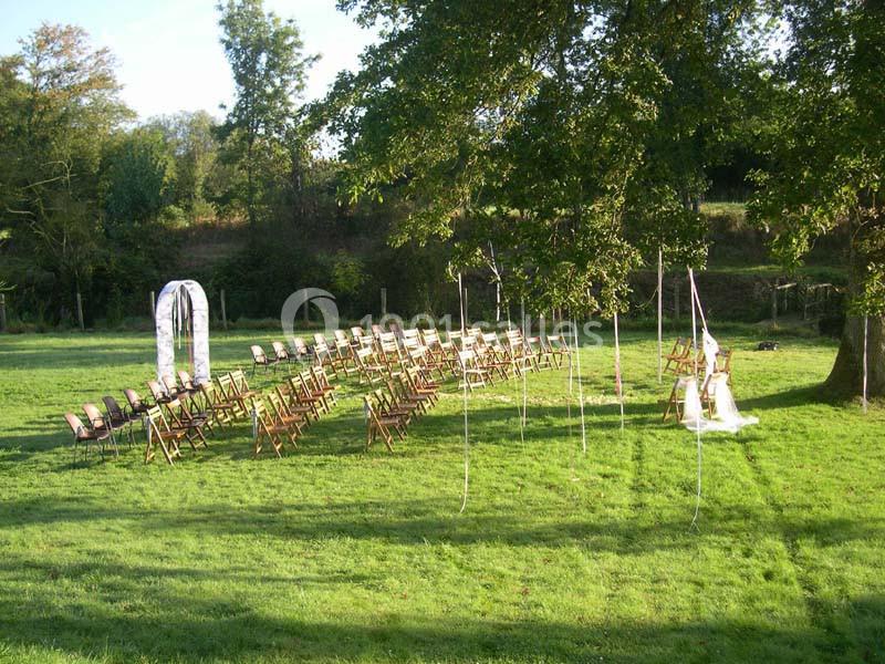 Chaises disposées en extérieur sur une pelouse, formant une allée centrale, avec une arche décorative à l'arrière.