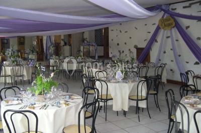 Salle décorée avec des tables hautes blanches, des nappes et des éléments suspendus dans un style épuré et chaleureux.