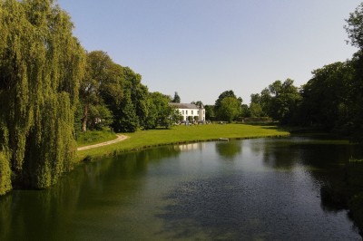 Miniature Location salle Hannut (Liège) - Château d'Avin #3 Manoir blanc entouré de pelouses et d'arbres, avec un étang au premier plan reflétant le bâtiment.