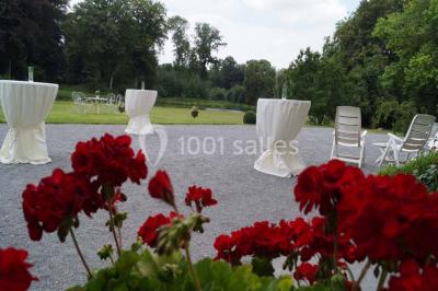 Salle de réunion avec une grande table en bois, chaises noires, bouteilles d'eau et vue sur l'extérieur par des baies…