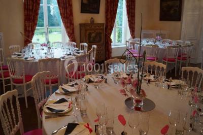Salle de réunion avec une grande table en bois, chaises noires, bouteilles d'eau et vue sur l'extérieur par des baies…