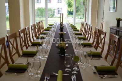 Salle de réunion avec une grande table en bois, chaises noires, bouteilles d'eau et vue sur l'extérieur par des baies…