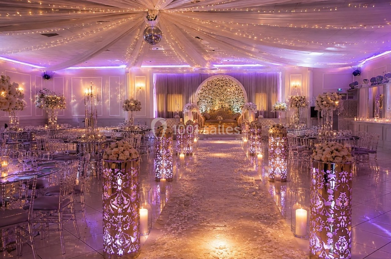 Salle de réception décorée avec des fleurs, des lumières tamisées et un plafond illuminé pour un événement festif.