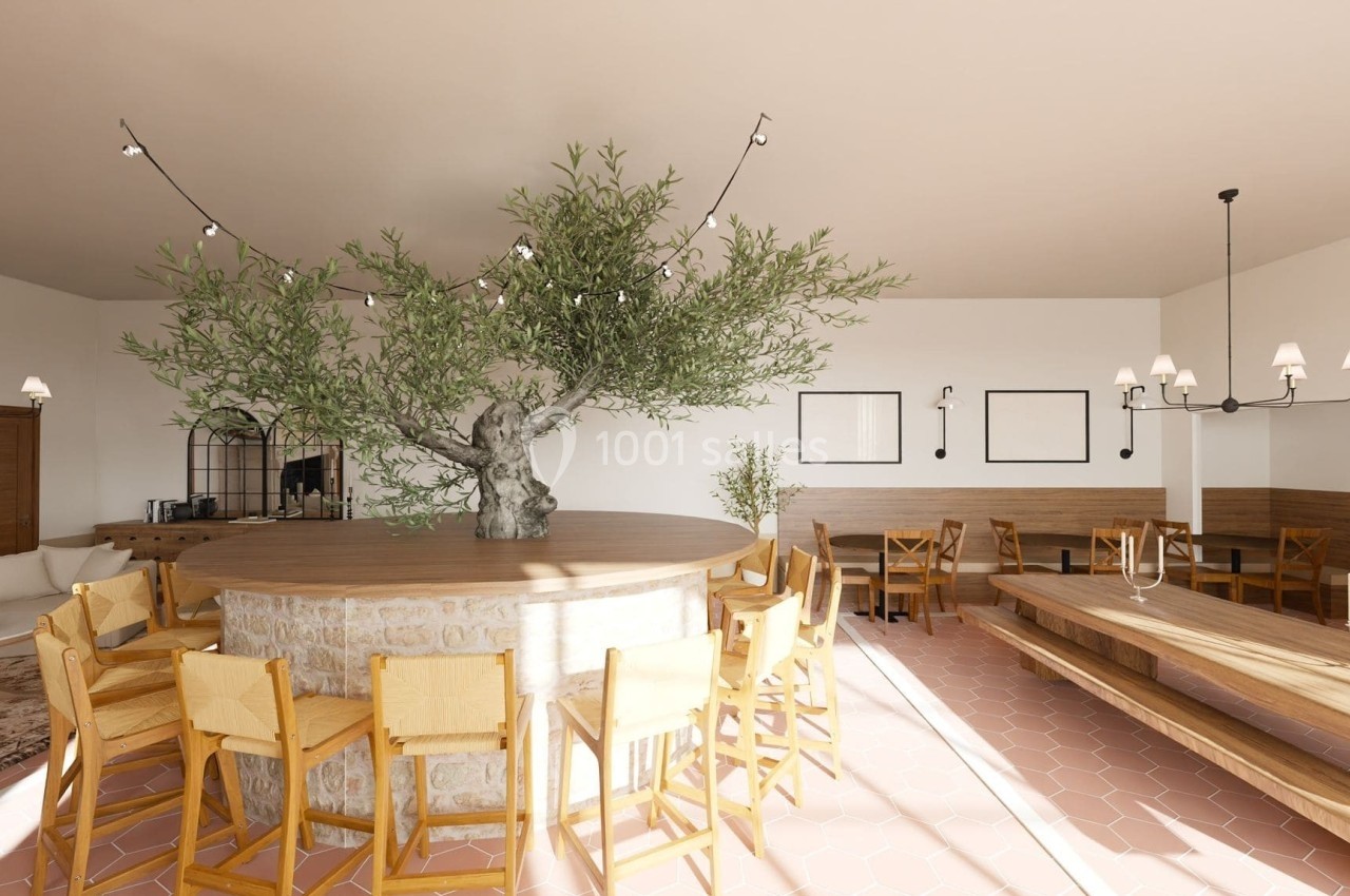Salle de restaurant lumineuse avec un olivier central entouré de chaises en bois et des tables en bois clair.