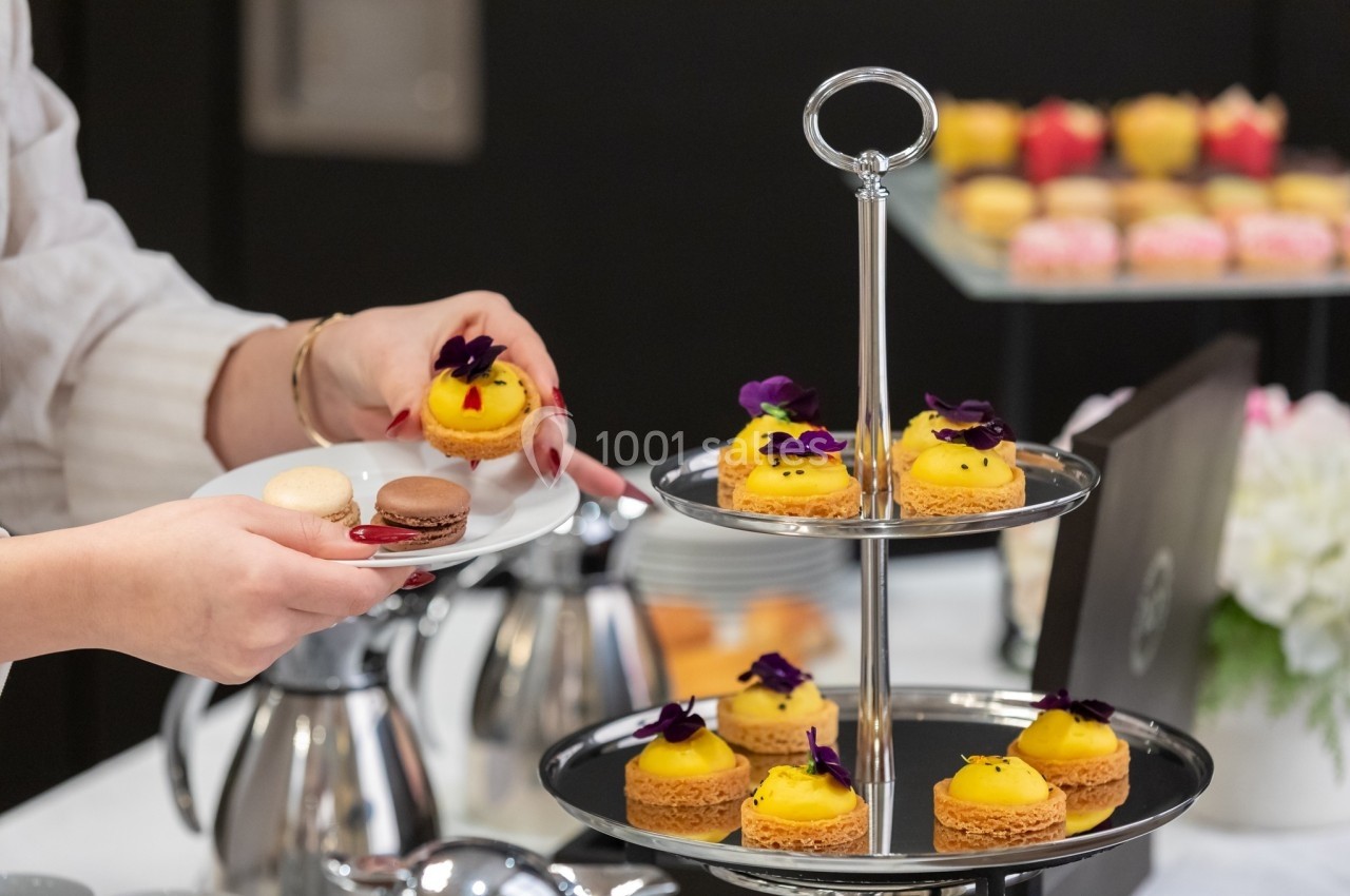 Plateau de pâtisseries élégantes avec macarons et desserts décorés de fleurs, servi lors d'un événement.