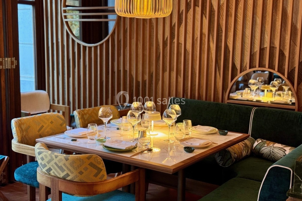 Table dressée avec vaisselle et verres dans un restaurant élégant, décoré de bois et éclairé par une suspension.