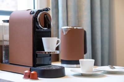 Sèche-cheveux noir dans un étui rigide ouvert de couleur marron, posé sur une surface claire.