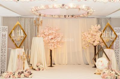 Décoration de salle avec fleurs roses, chandeliers dorés et rideaux scintillants dans un cadre élégant et lumineux.