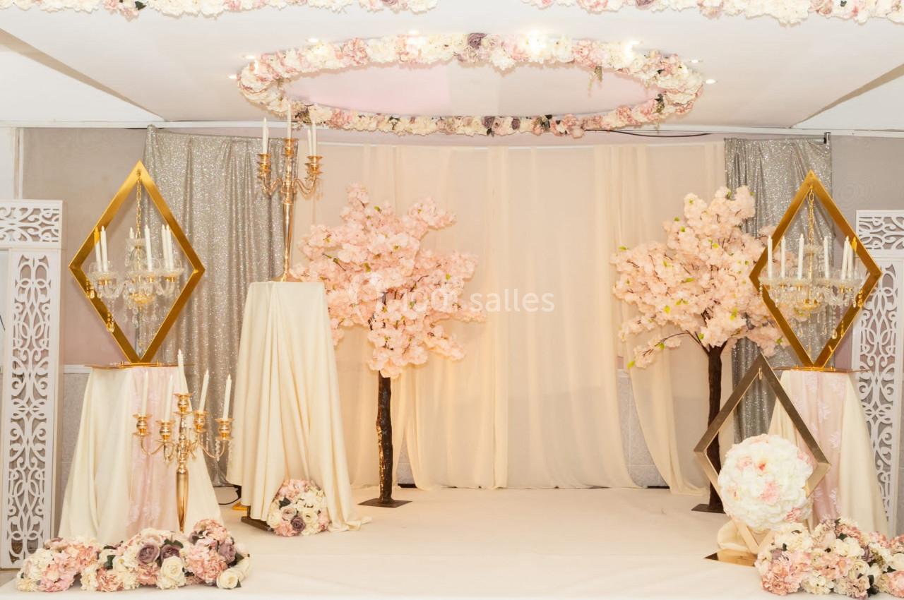 Décoration de salle avec fleurs roses, chandeliers dorés et rideaux scintillants dans un cadre élégant et lumineux.