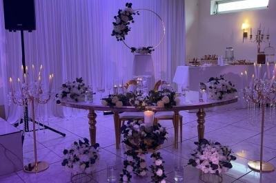Décoration de salle avec fleurs roses, chandeliers dorés et rideaux scintillants dans un cadre élégant et lumineux.