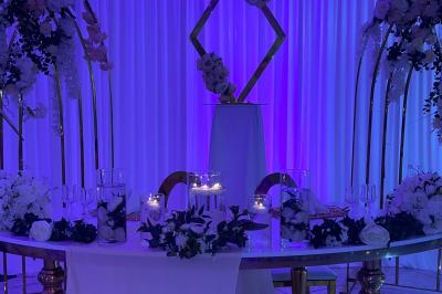 Décoration de salle avec fleurs roses, chandeliers dorés et rideaux scintillants dans un cadre élégant et lumineux.