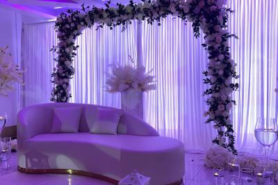 Décoration de salle avec fleurs roses, chandeliers dorés et rideaux scintillants dans un cadre élégant et lumineux.