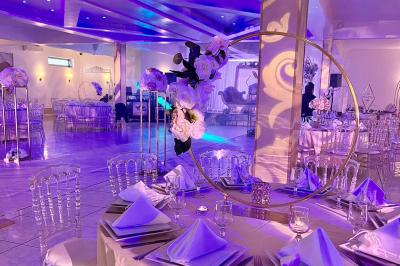 Décoration de salle avec fleurs roses, chandeliers dorés et rideaux scintillants dans un cadre élégant et lumineux.