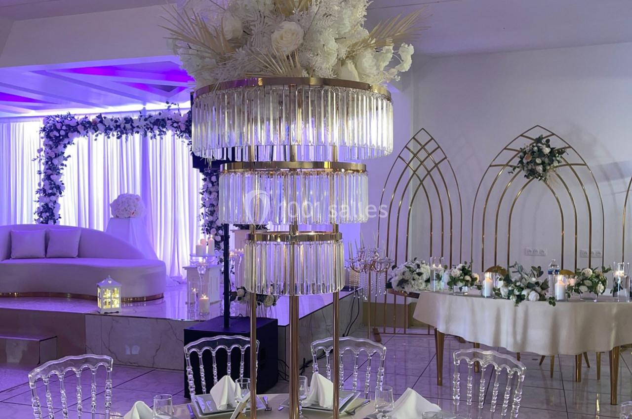 Centre de table élégant avec pampas et fleurs blanches, entouré de décorations lumineuses dans une salle de réception.