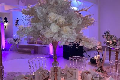 Décoration de salle avec fleurs roses, chandeliers dorés et rideaux scintillants dans un cadre élégant et lumineux.