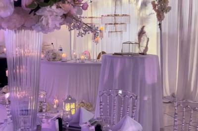 Décoration de salle avec fleurs roses, chandeliers dorés et rideaux scintillants dans un cadre élégant et lumineux.