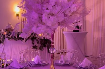 Décoration de salle avec fleurs roses, chandeliers dorés et rideaux scintillants dans un cadre élégant et lumineux.