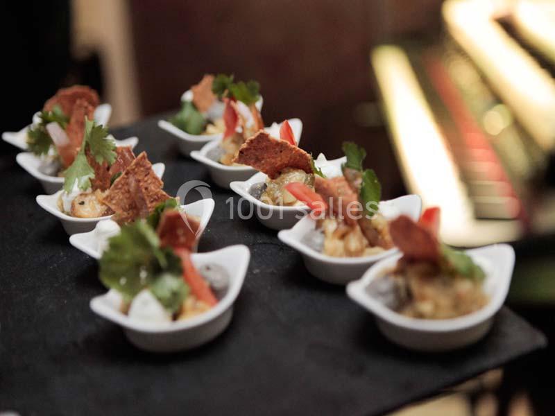 Petites portions de plats gastronomiques servies dans des cuillères blanches, décorées de légumes et d'herbes fraîches.