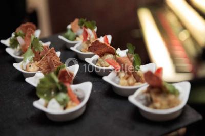 Assiettes individuelles de poisson sur sauce rouge, garnies de coriandre et de croûtons, servies sur un plateau.