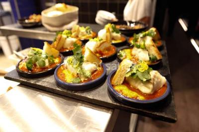 Assiettes individuelles de poisson sur sauce rouge, garnies de coriandre et de croûtons, servies sur un plateau.