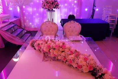 Salle colorée avec petites tables et chaises pour enfants, entourées de canapés aux motifs vifs sur un tapis décoré.