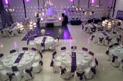 Salle colorée avec petites tables et chaises pour enfants, entourées de canapés aux motifs vifs sur un tapis décoré.