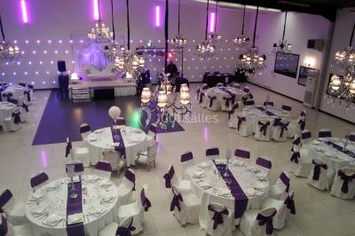 Salle colorée avec petites tables et chaises pour enfants, entourées de canapés aux motifs vifs sur un tapis décoré.